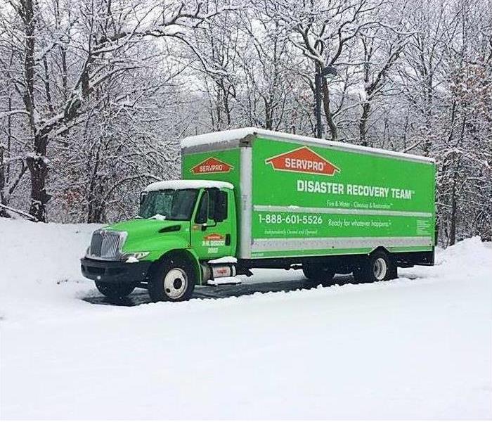 green truck parked with snow on the ground